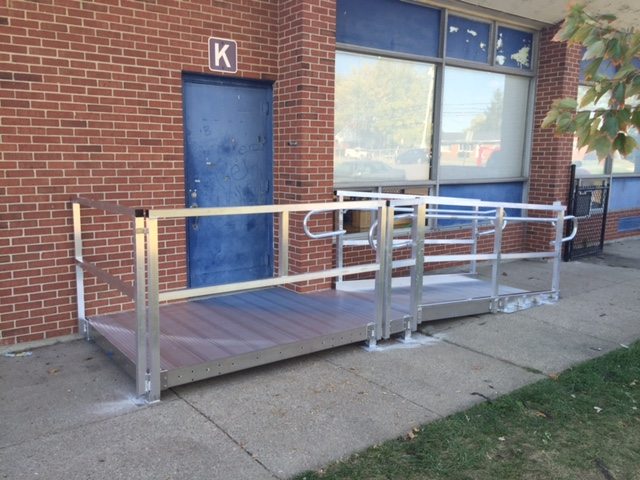 Permanent accessibility ramp with handrails at a school entrance, the standard our trailer ramps match