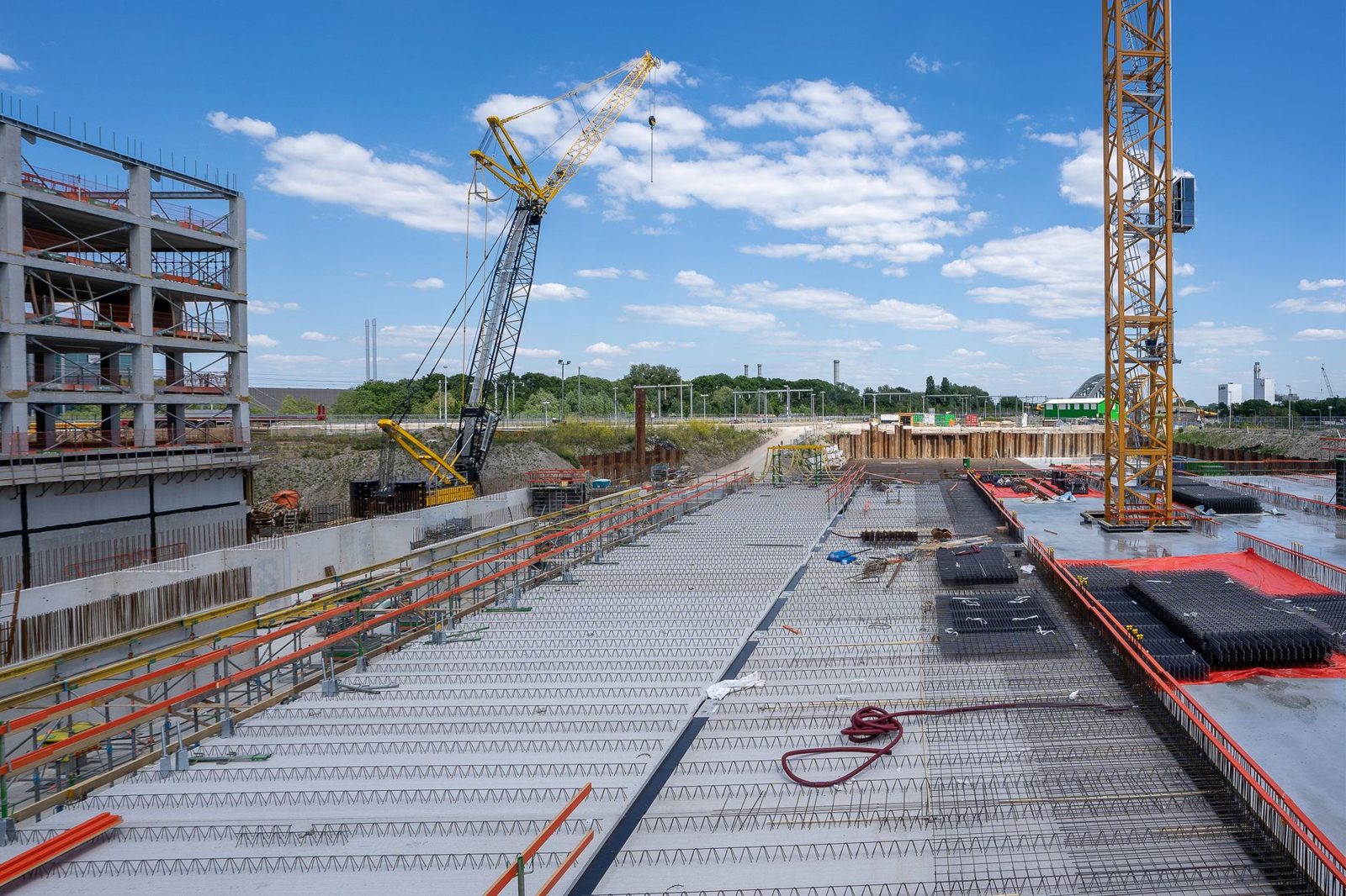 A large jobsite with tower cranes and poured decks