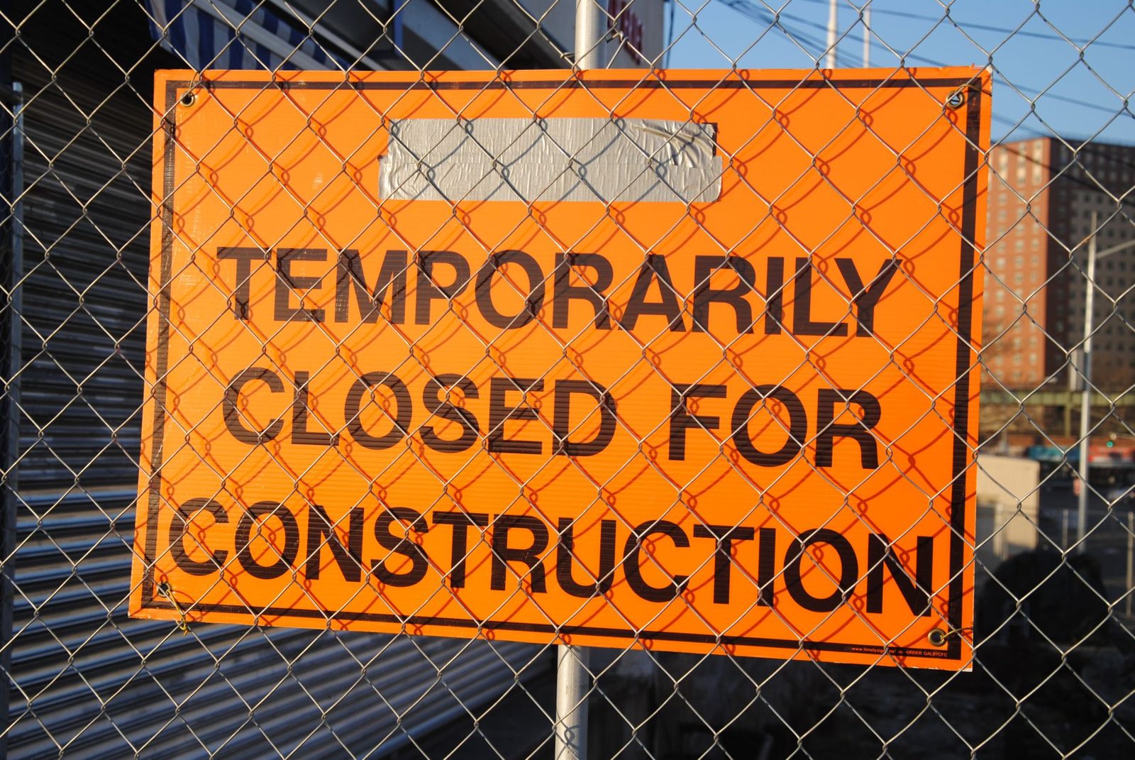 A temporarily closed for construction sign on a fence