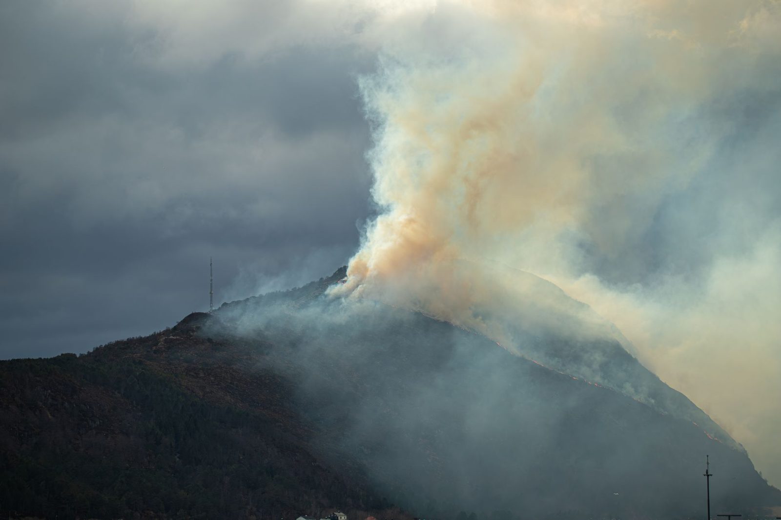 Wildfire smoke rising over a chaparral ridge