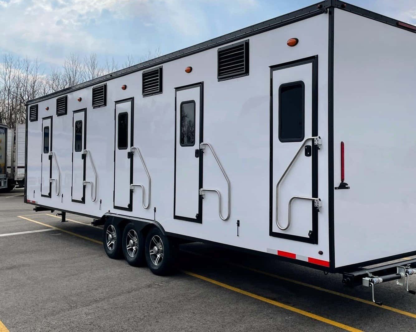 White bunkhouse sleeper trailer with multiple private entry doors and steps