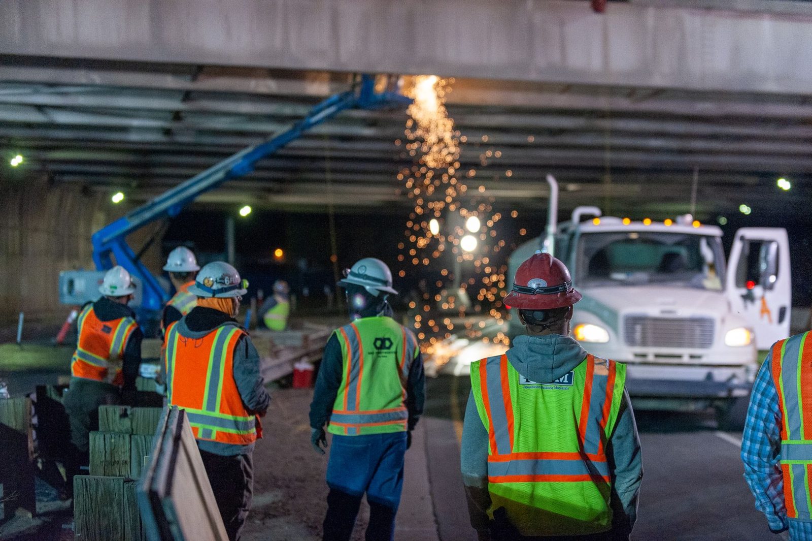 A night crew in safety vests working under an overpass