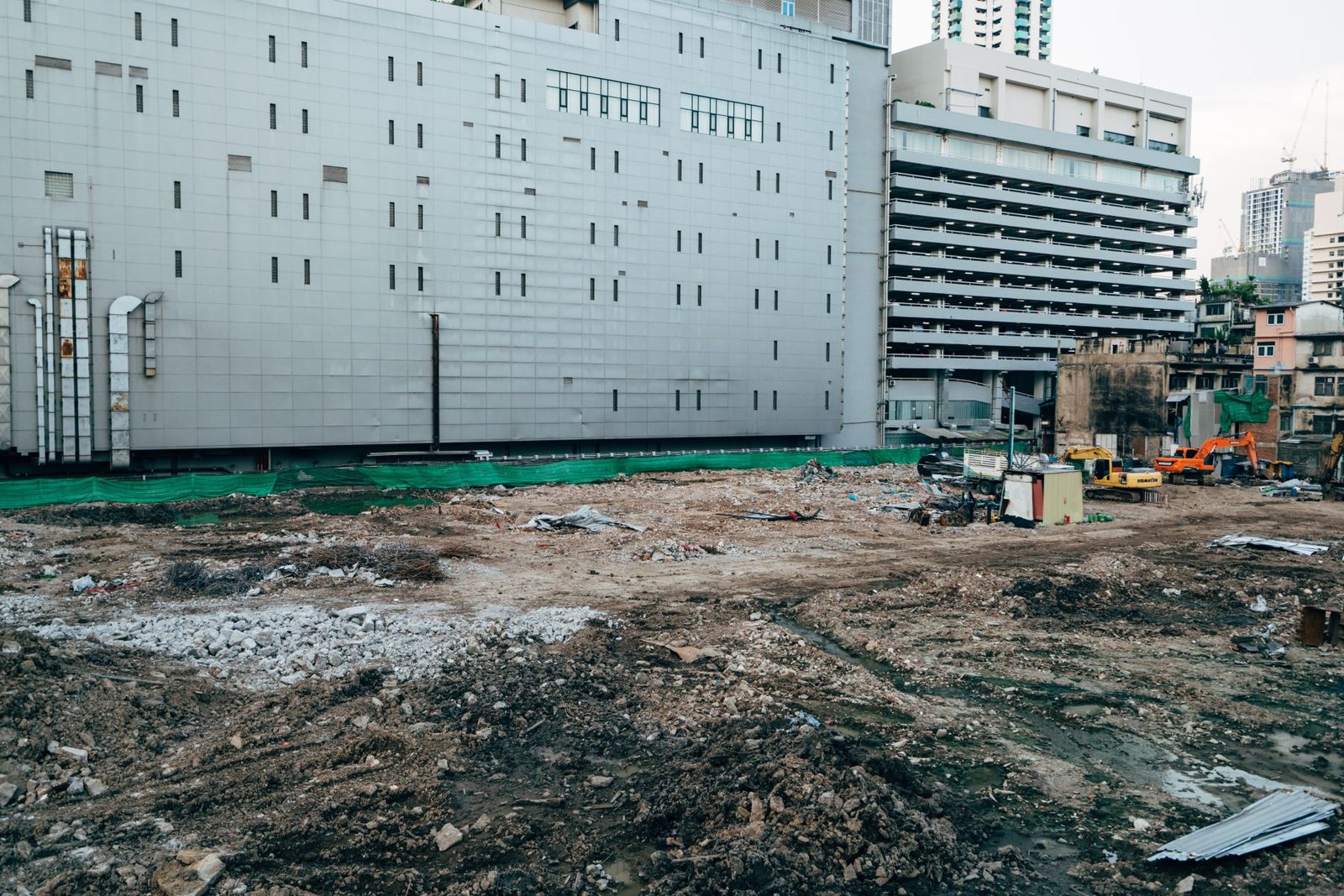 A large new building rising beside a cleared dirt lot