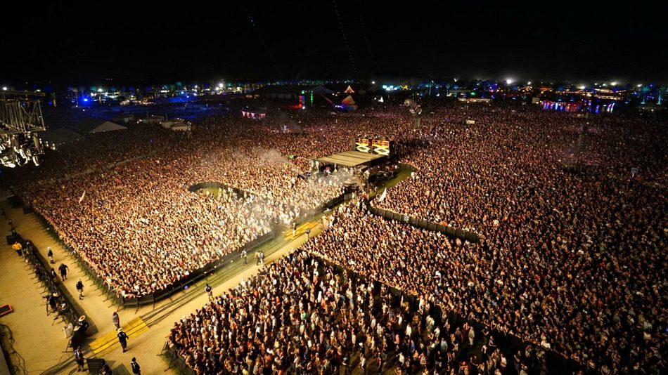 Aerial view of a massive festival crowd at a large outdoor event site