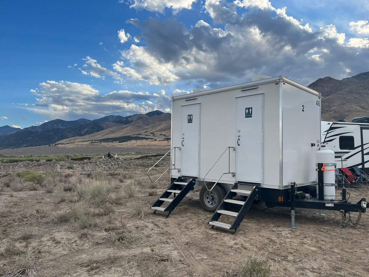 Compact 2 station luxury restroom trailer parked with both suite doors open and entry steps folded down
