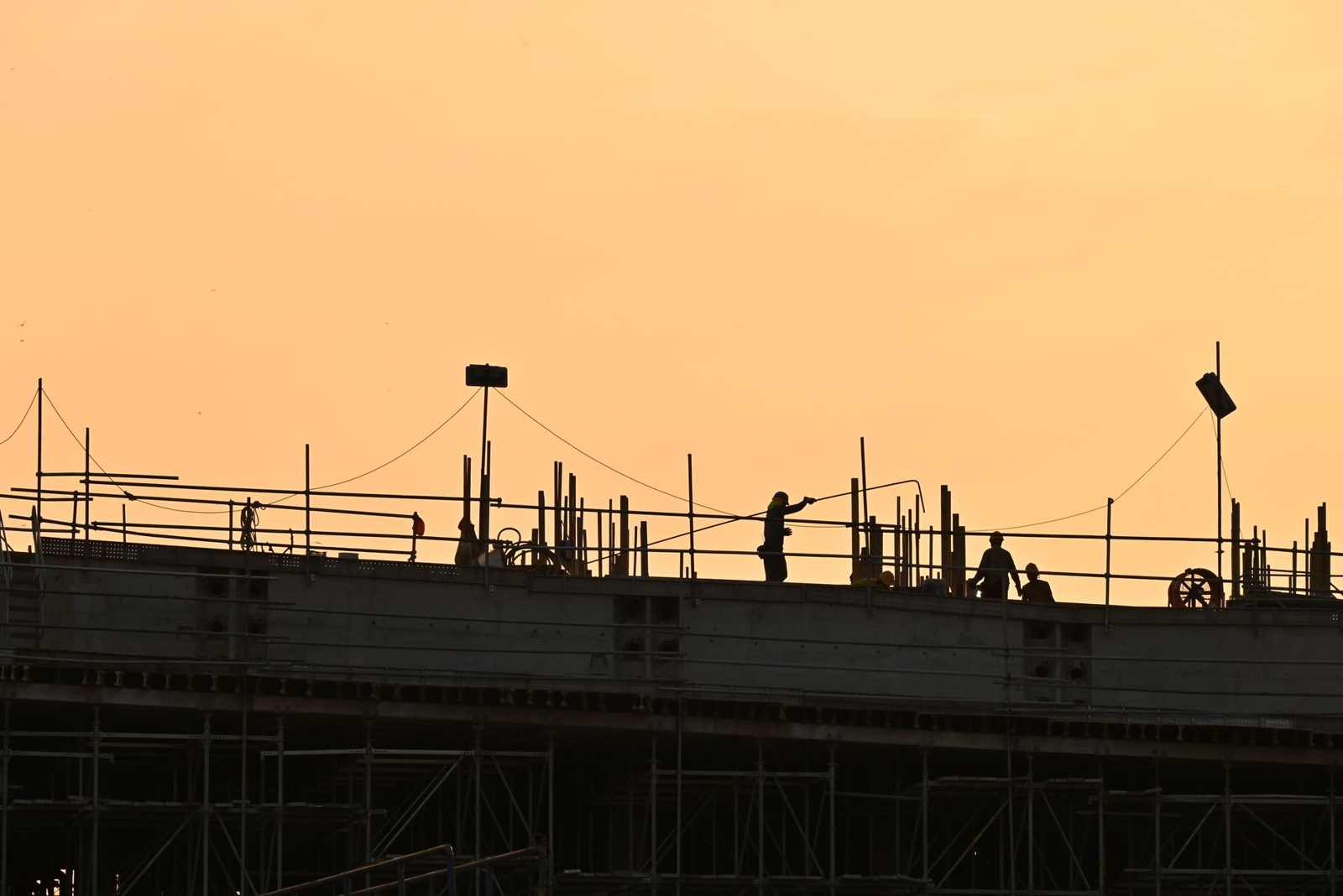A crew working atop a structure at sunset