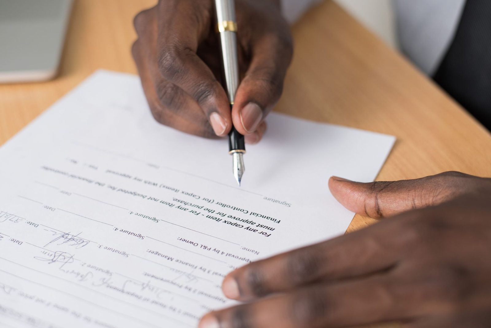 A hand signing a contract form