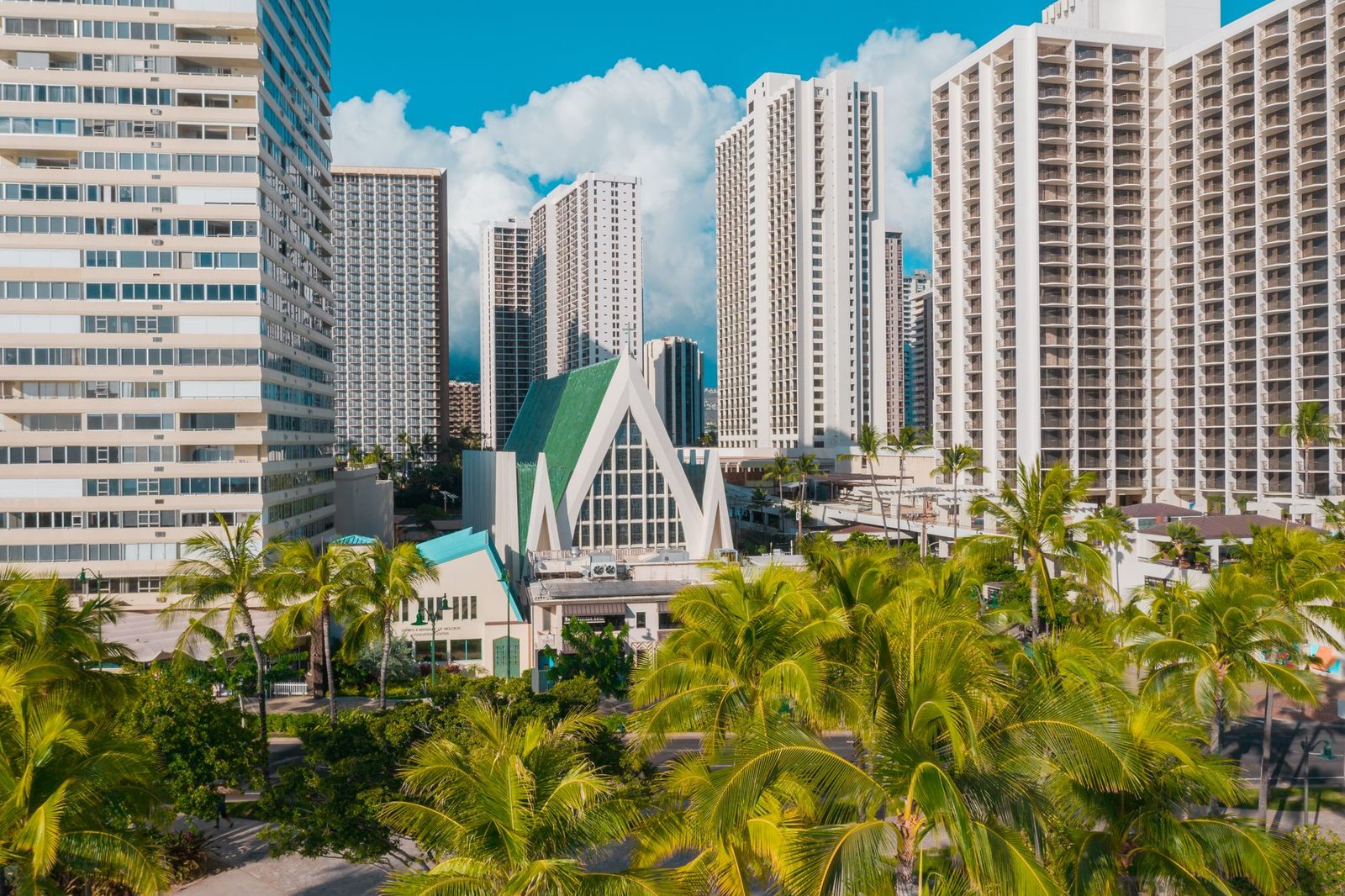 Waikiki towers and palm trees around a small church in Honolulu