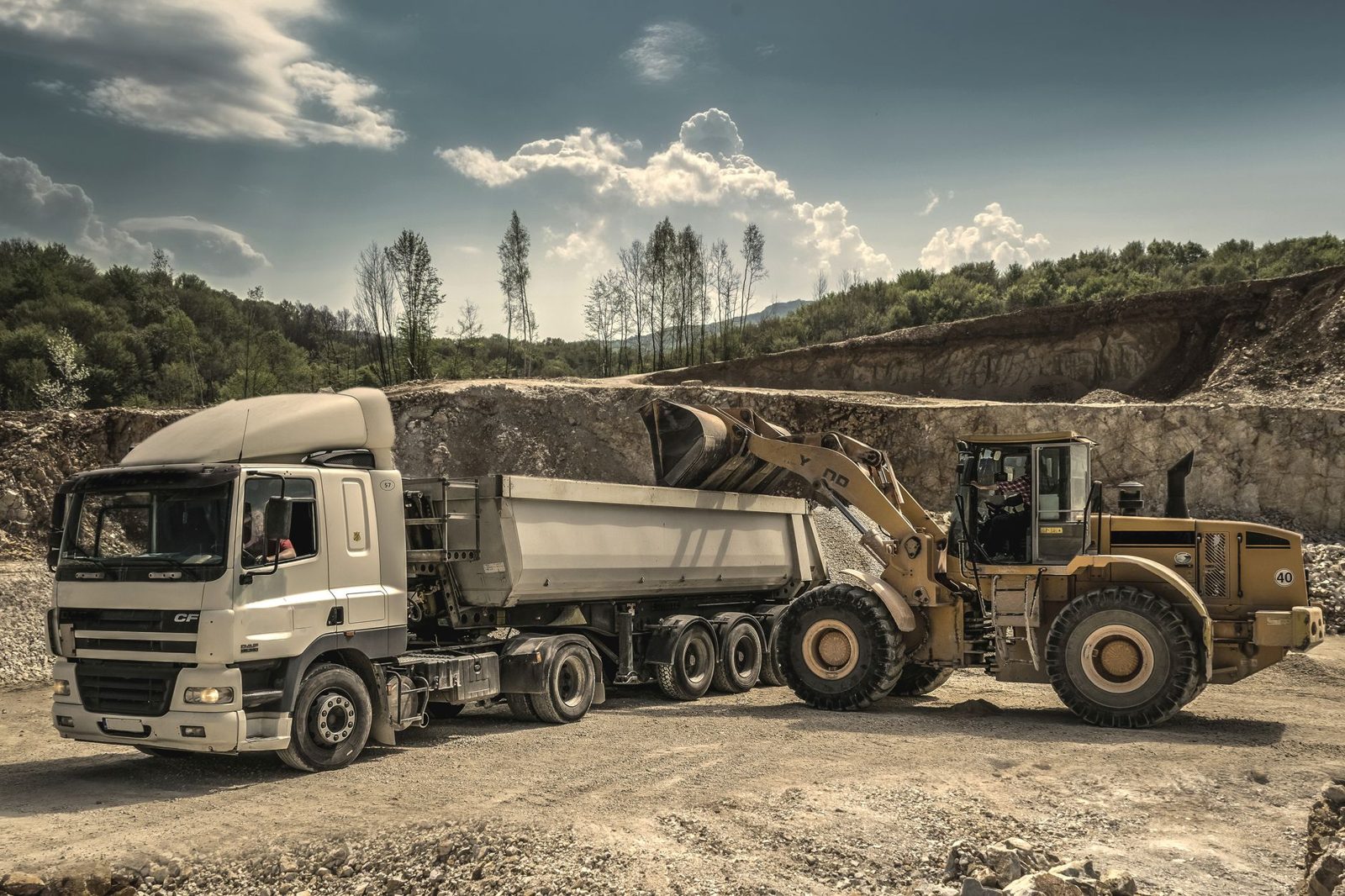 A dump truck and loader working on a gravel pad