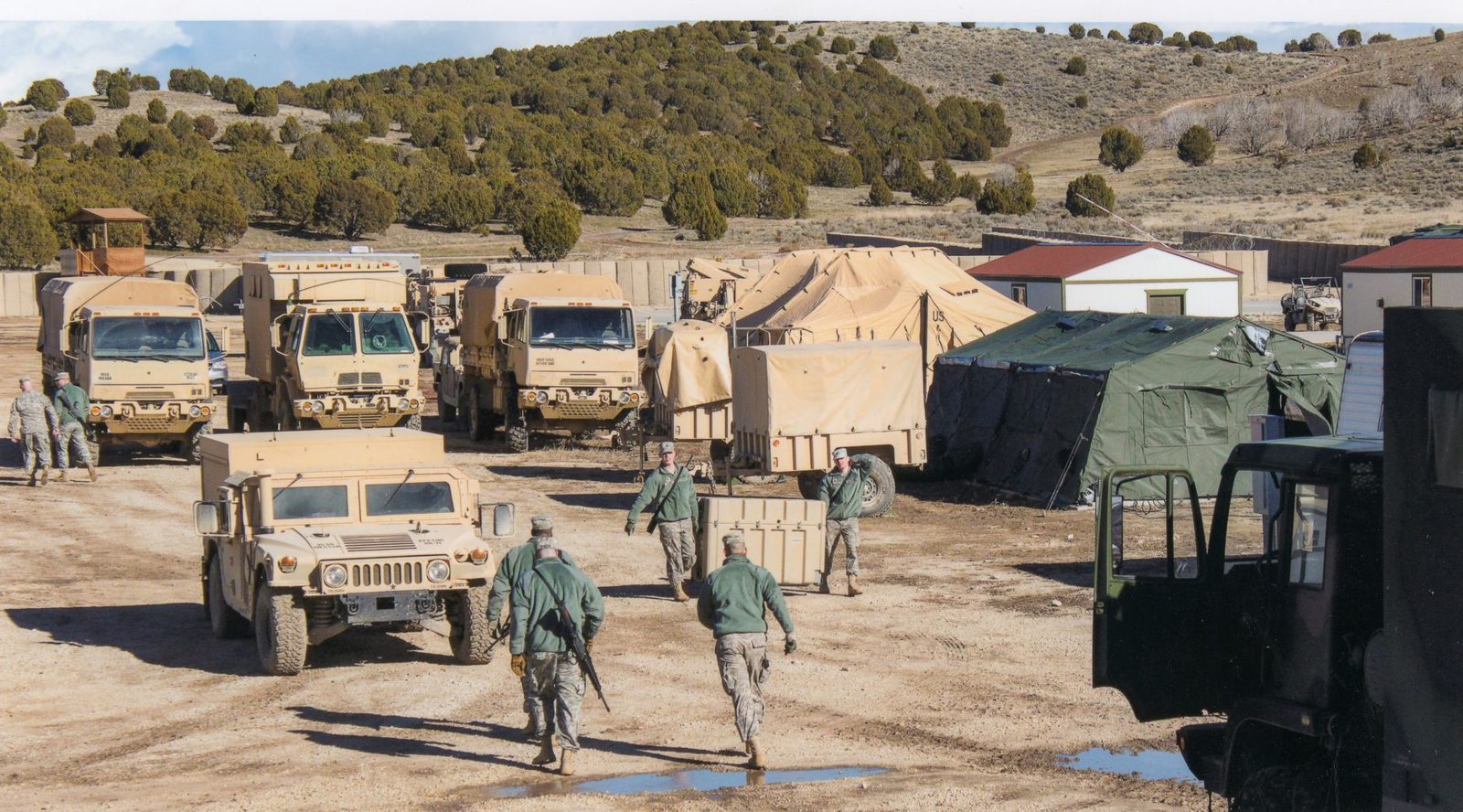 Military trucks and vehicles parked at a field camp