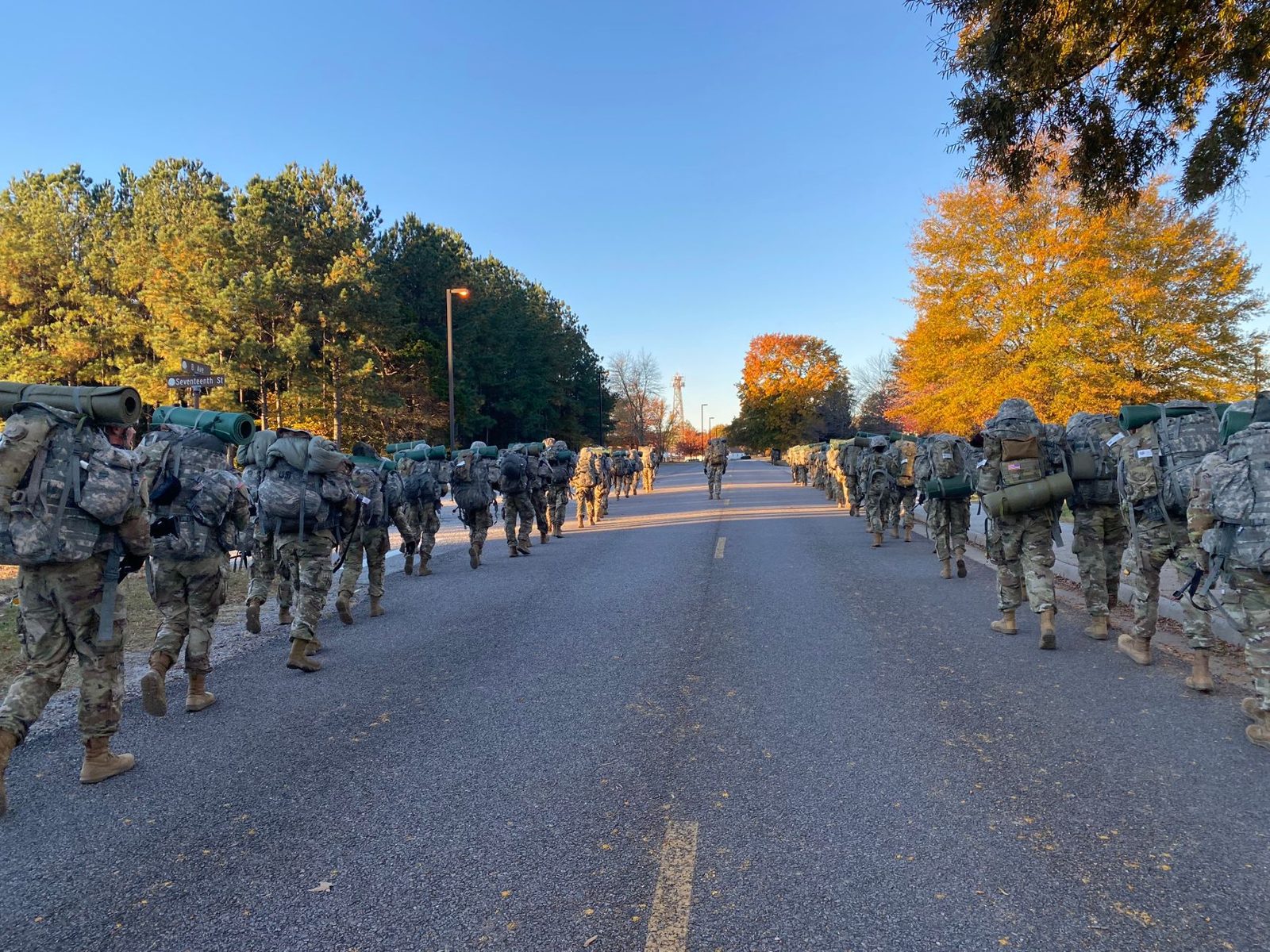 Troops marching along a tree lined road on base