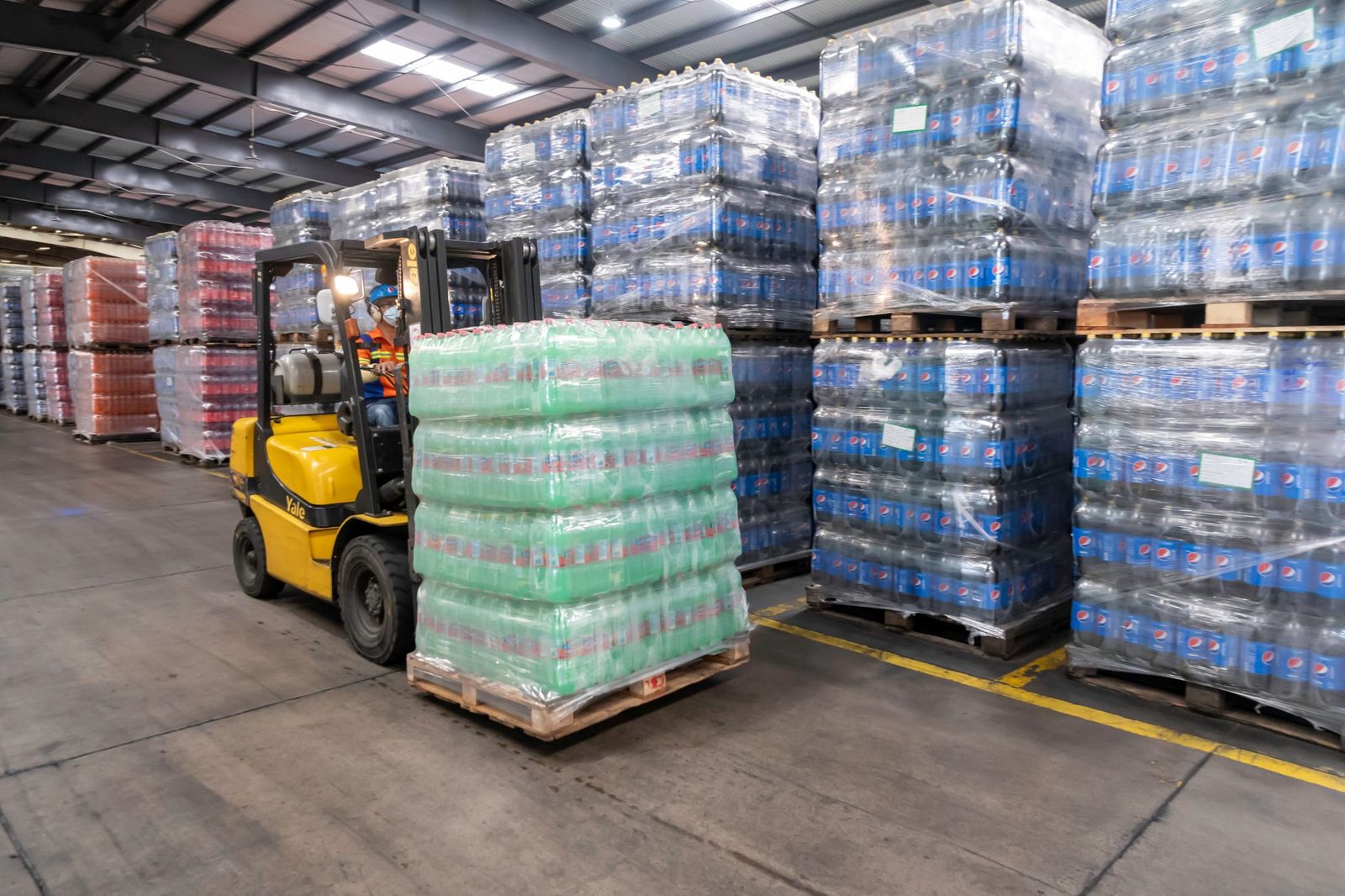 Pallets of bottled water being moved in a warehouse