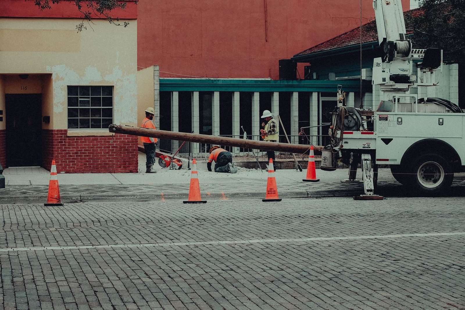 A utility crew with a crane truck working inside a coned off street