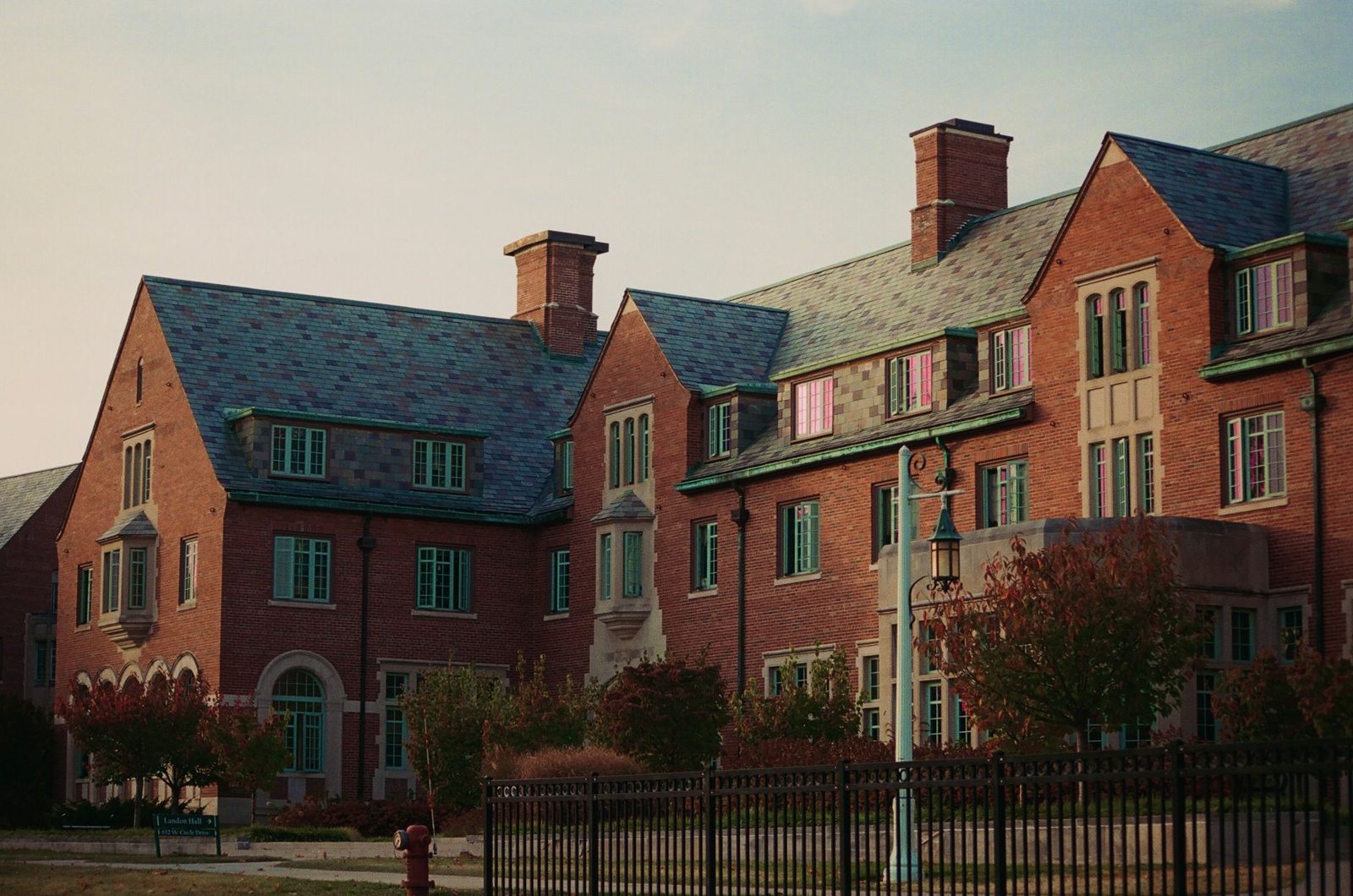 A brick campus building behind an iron fence