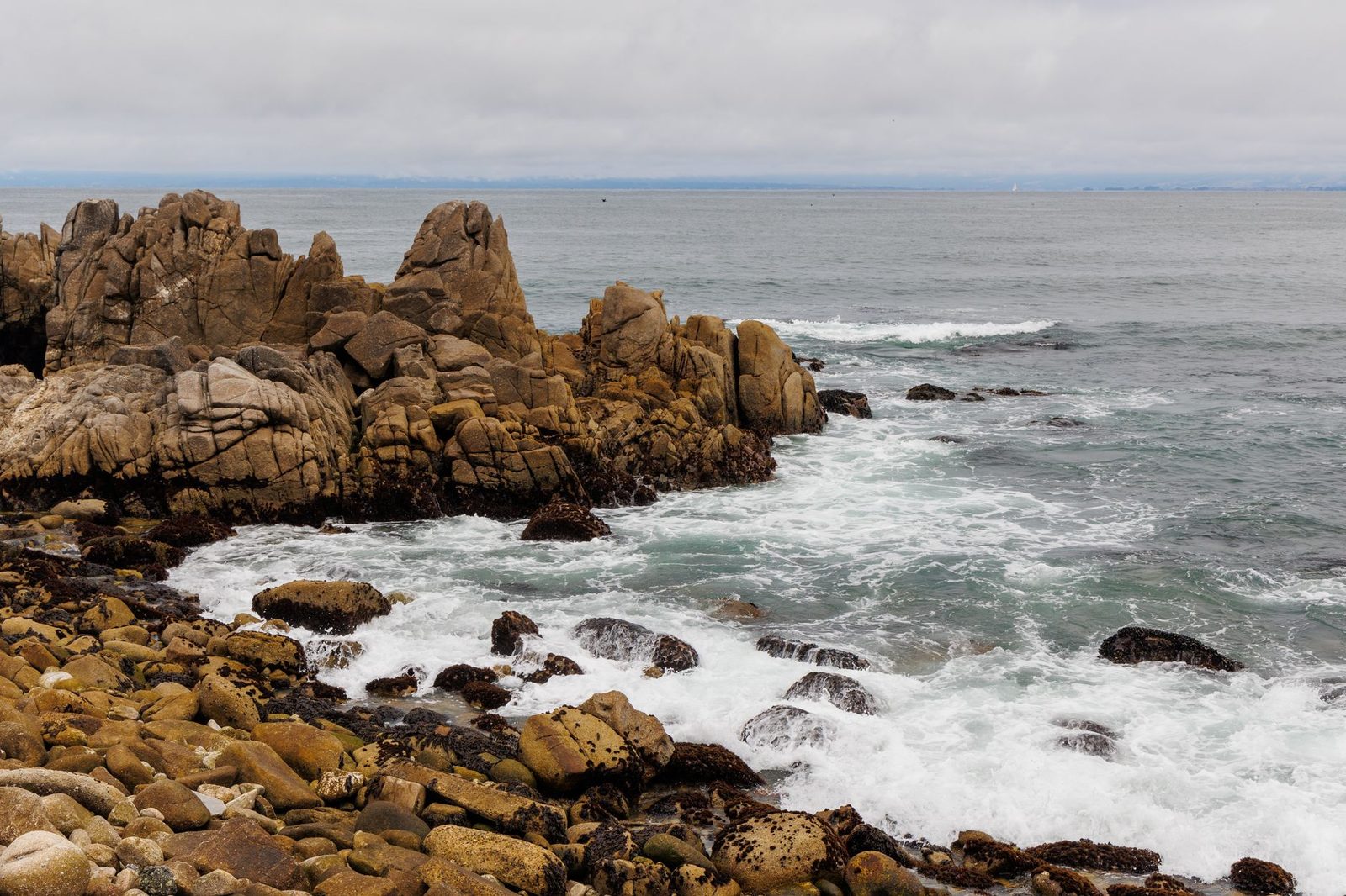 A rocky Pacific shoreline with surf rolling in