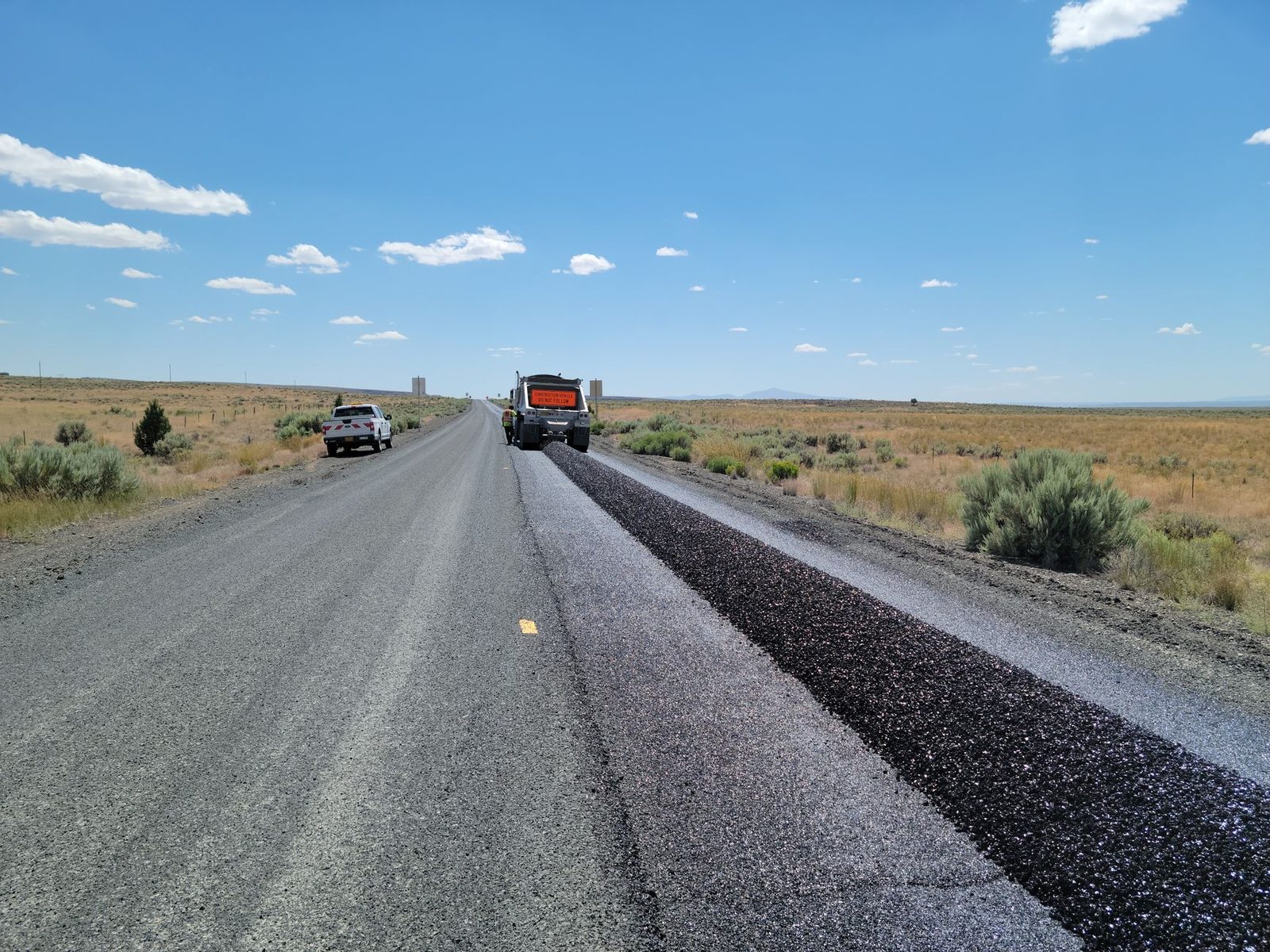 A highway road crew paving a desert freeway work zone in summer heat near Las Vegas