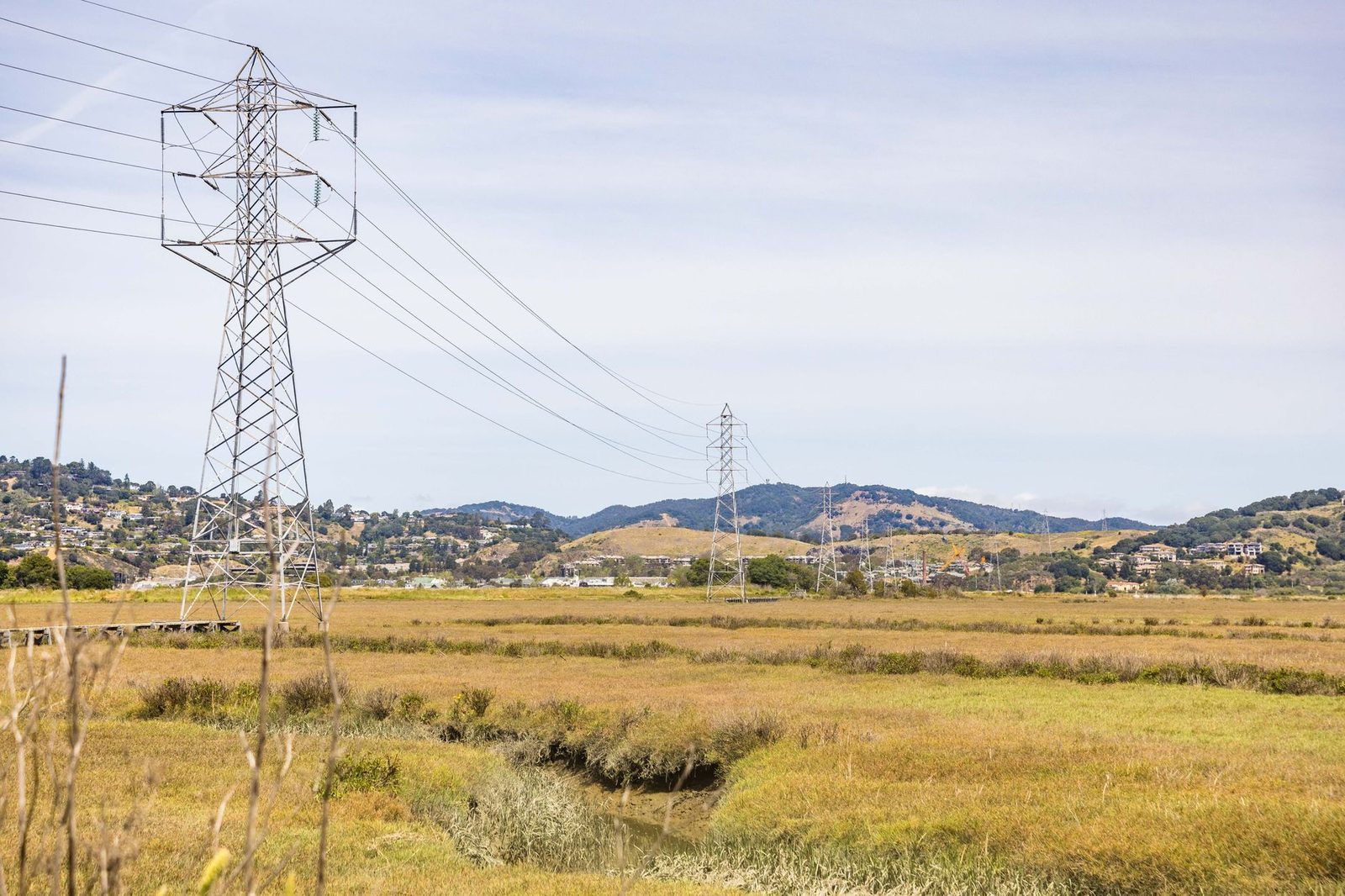 High-voltage transmission towers crossing dry golden hills